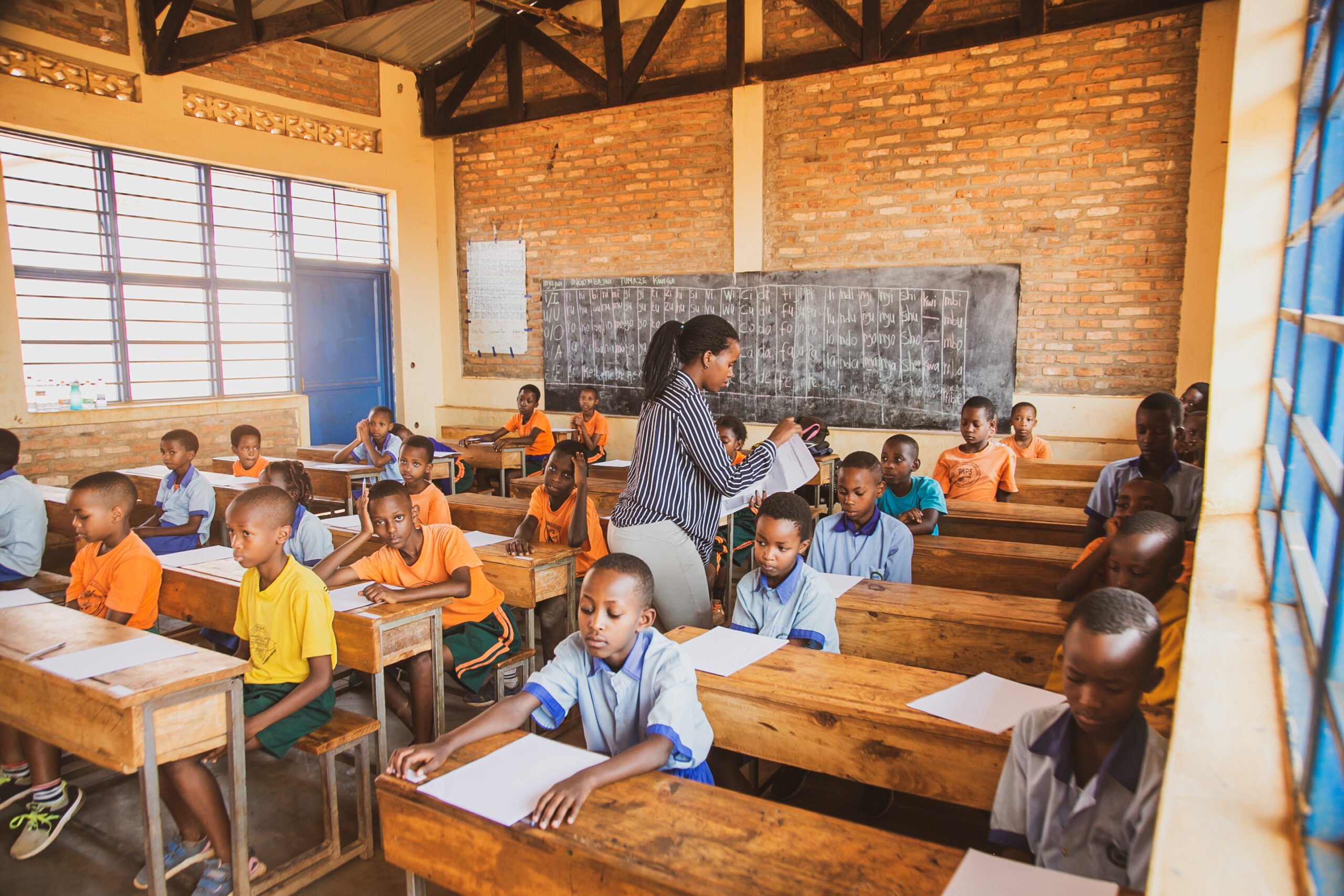 Students sitting in Rwandan school room, facing forward each at their own desk.
