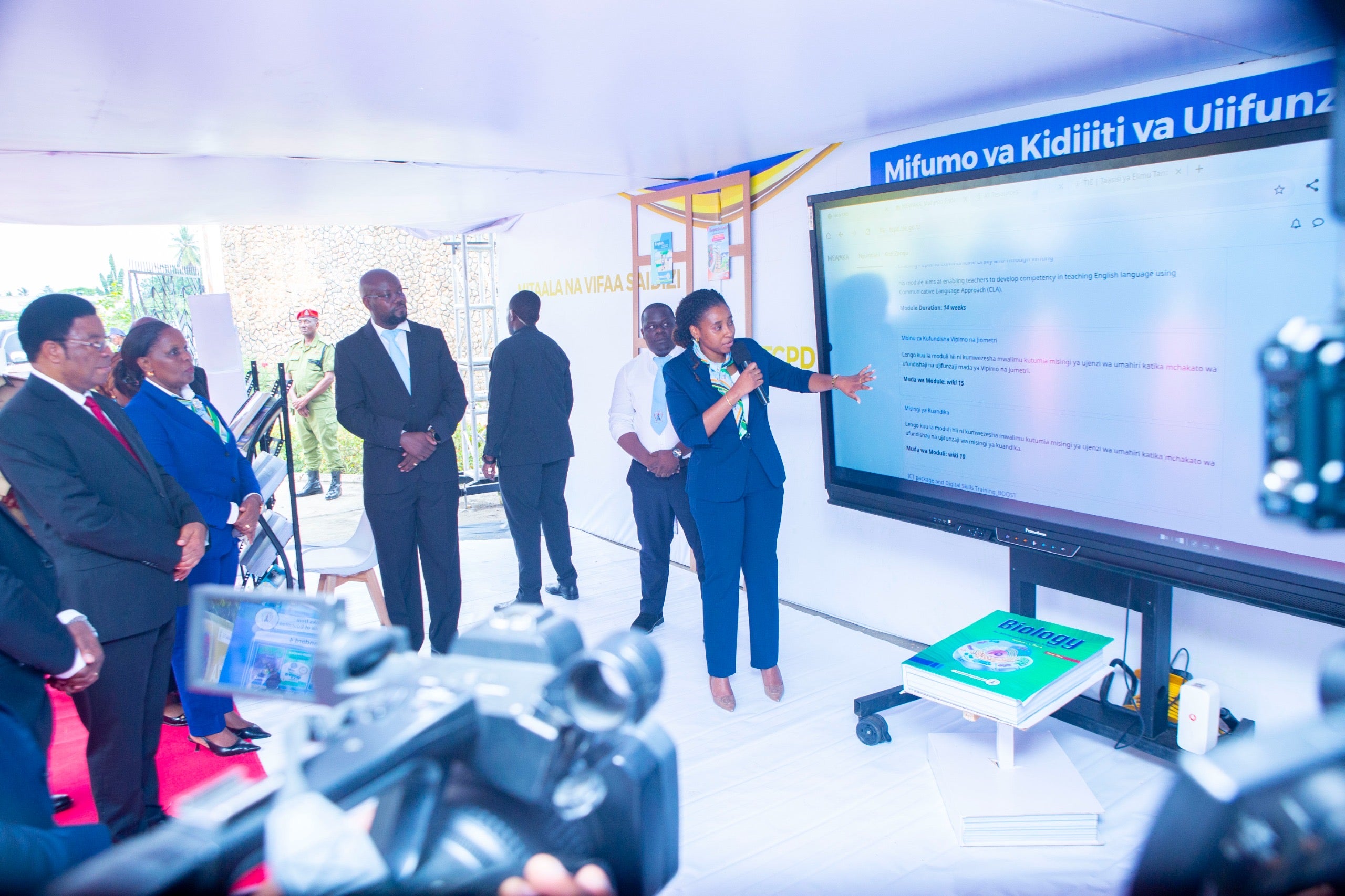 A group of individuals stand in front of projector screen giving a talk on recent research