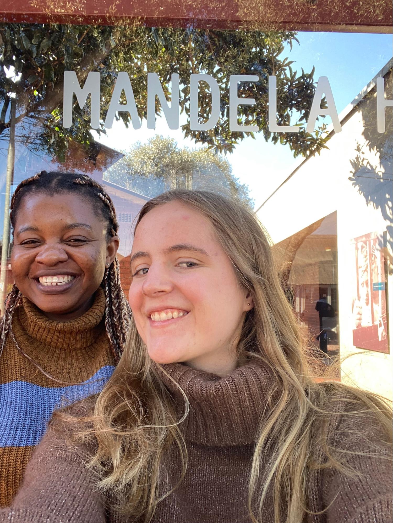 Two women smiling in front of a sign reading 