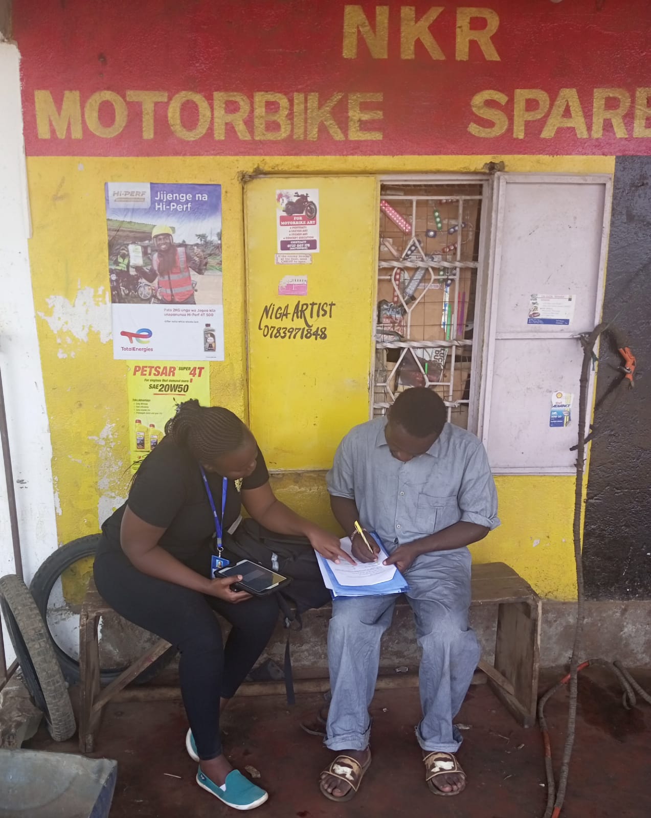 Two people sitting down, one writing on a piece of paper