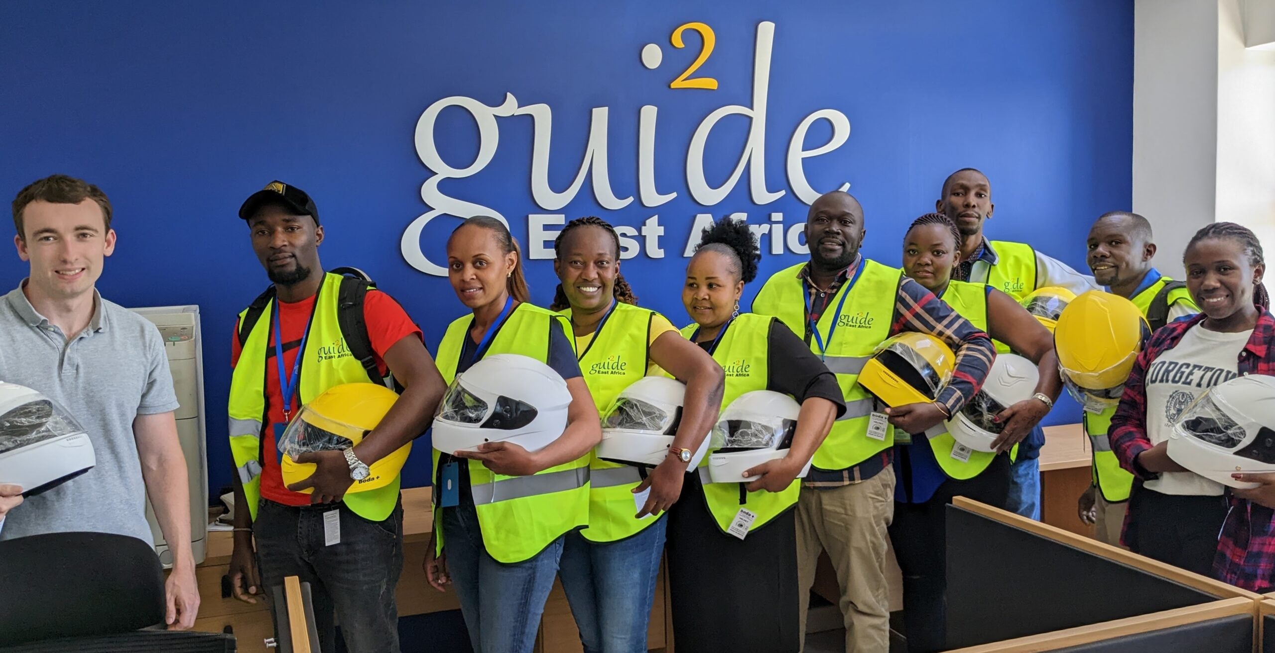 Group of people wearing hi-vis safety vests holding motorcycle helmets