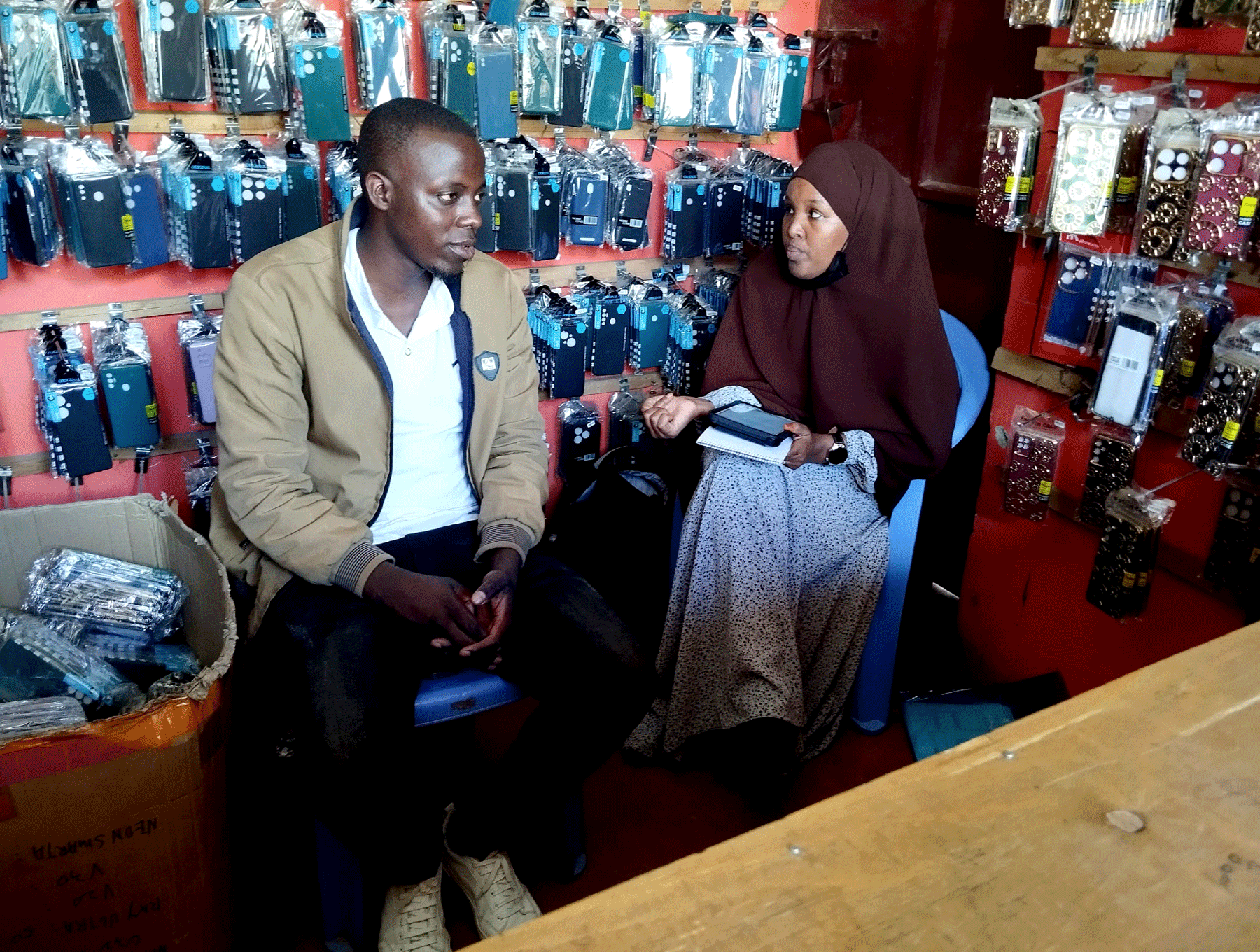 A surveyor conducting research with owner of cell phone store